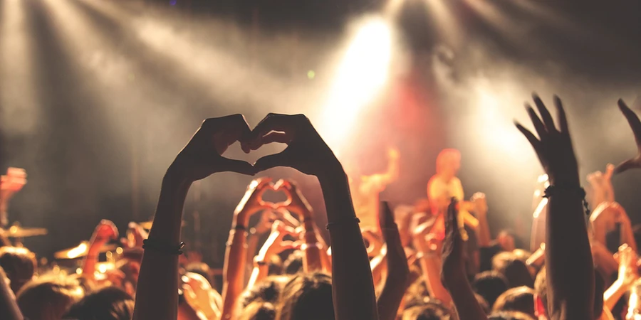 Crowd at a concert forming heart shapes with their hands, representing a loyal VIP segment of highly engaged customers