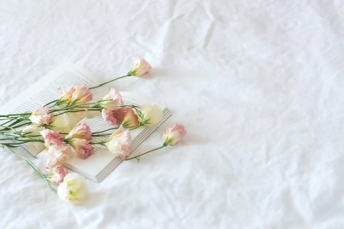 Soft pastel flowers resting on an open book over white fabric, representing aesthetic inspiration for Squarespace wedding website examples.